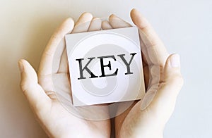 White paper with text KEYÂ in male hands on a white background